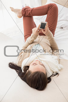 Pretty brunette sending a text on bed