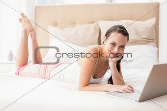 Pretty brunette using laptop on bed