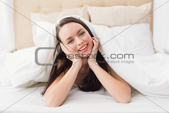Pretty brunette smiling at camera in bed
