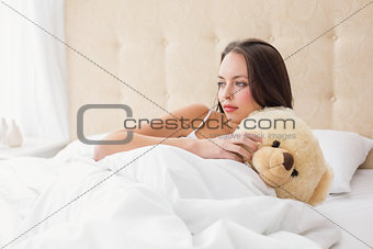 Pretty brunette under the duvet with teddy bear