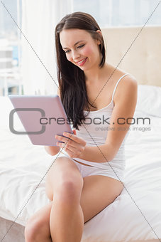 Pretty brunette using tablet pc on bed