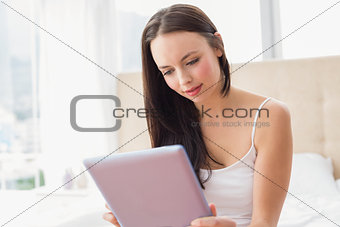 Pretty brunette using tablet pc on bed