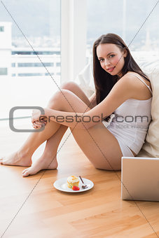 Pretty brunette using laptop sitting on floor