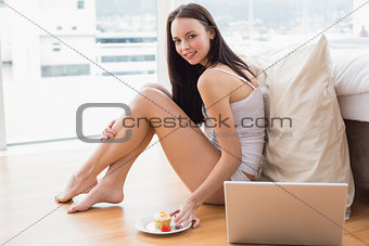 Pretty brunette using laptop sitting on floor