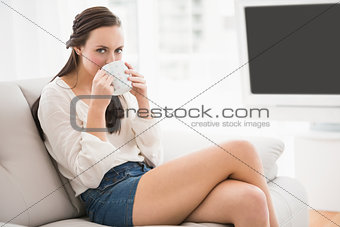 Pretty brunette drinking coffee on the couch