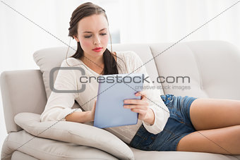 Pretty brunette using tablet on the couch