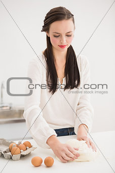 Pretty brunette making dough on counter