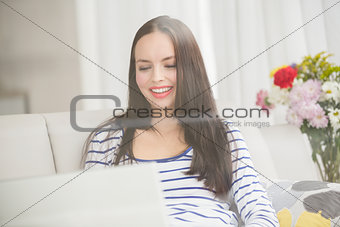 Pretty brunette using laptop on couch