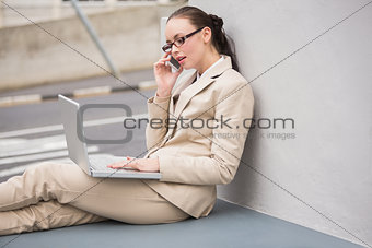 Young businesswoman using laptop on the phone