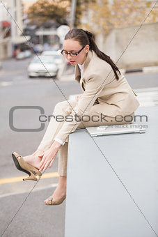 Young businesswoman adjusting her shoe