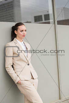 Young businesswoman leaning against wall