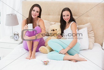 Pretty friends having coffee on bed
