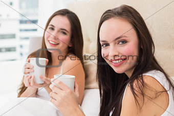Pretty friends having coffee in bed