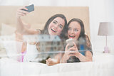 Pretty friends taking a selfie on bed