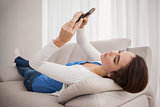 Pretty brunette sending a text on couch