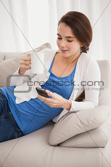 Pretty brunette sending a text on couch
