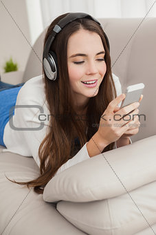 Pretty brunette listening to music on the couch