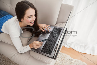 Pretty brunette shopping online on couch