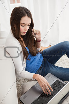 Pretty brunette using laptop on the floor