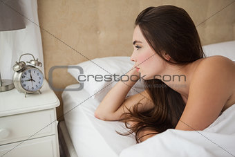 Pretty brunette looking at her alarm clock