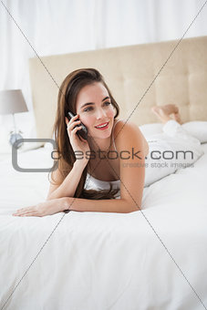 Pretty brunette talking on the phone in bed