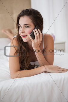 Pretty brunette talking on the phone in bed