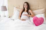 Pregnant brunette sitting in bed