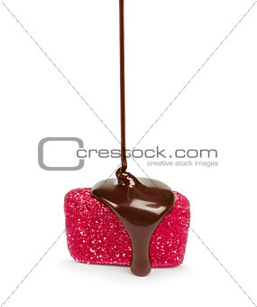 Chocolate flows on a pink jelly candies isolated on a white