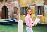 Portrait of happy young woman with map in venice, italy
