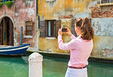 Young woman in venice, italy taking photo. rear view