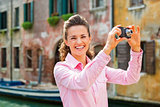 Smiling young woman taking photo in venice, italy
