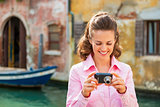 Happy young woman checking photos in camera in venice, italy