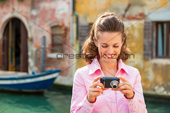 Happy young woman checking photos in camera in venice, italy