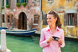 Happy young woman with photo camera looking on copy space while 