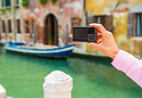 Closeup on young woman taking photo in venice, italy