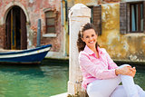 Portrait of smiling young woman sitting on street in venice, ita