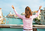 Happy young woman standing on bridge with grand canal view in ve