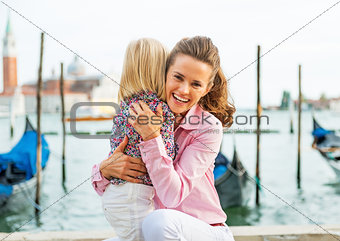 Portrait of happy mother and baby hugging on grand canal embankm