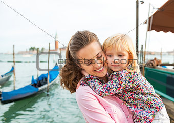 Portrait of happy mother and baby hugging on grand canal embankm