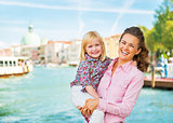 Portrait of happy mother and baby standing on grand canal embank