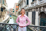 Happy young woman standing on bridge in venice, italy