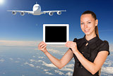 Beautiful businesswoman holding tablet PC. Blue sky, clowds and jet airliner as backdrop