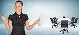 Beautiful businesswoman holding blank paper sheet and felt pen ready to use.  Beside is big conference table with chairs