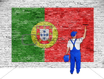 house painter covers brick wall with flag of Portugal