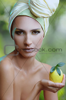 beautiful woman in yellow scarf on her head with lemon in hand over nature background