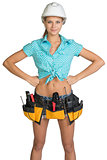 Pretty girl in helmet, shorts, shirt and tool belt with tools