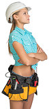 Looking up pretty girl in helmet, shorts, shirt and tool belt with tools