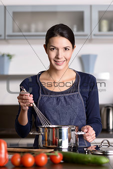 Happy friendly young housewife cooking dinner