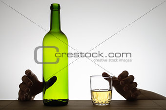 Hands reaching for a glass and a bottle