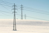 High voltage electricity power pylon on snowy field